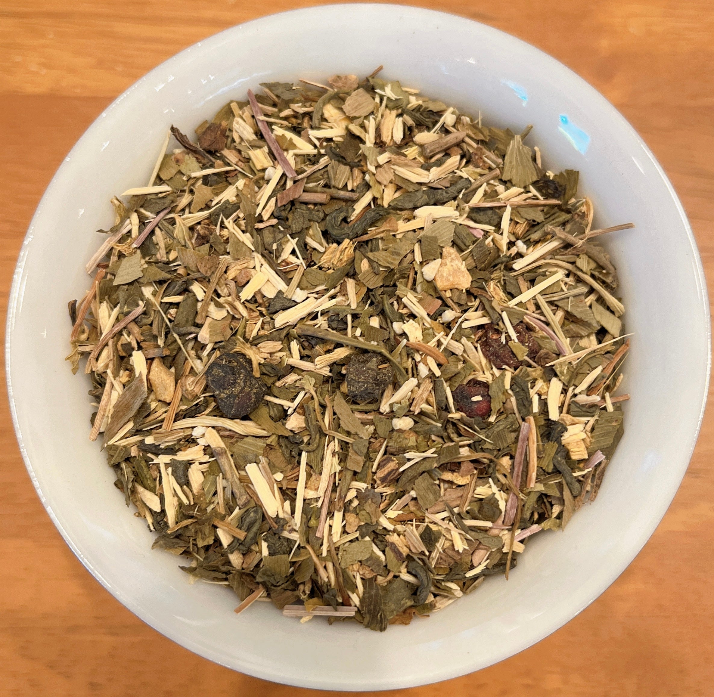 Herbal tea mix in a white bowl on a wooden surface