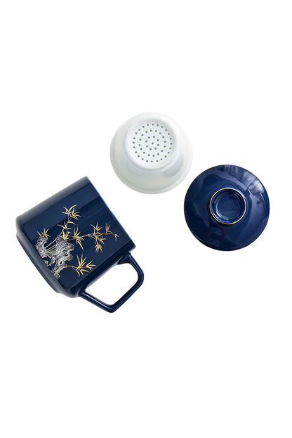 Navy blue mug with gold designs, white strainer, and blue lid on a white background