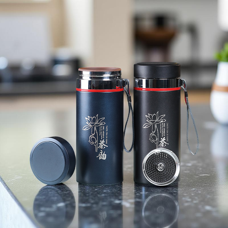 Two black thermos bottles with floral designs on a kitchen counter.