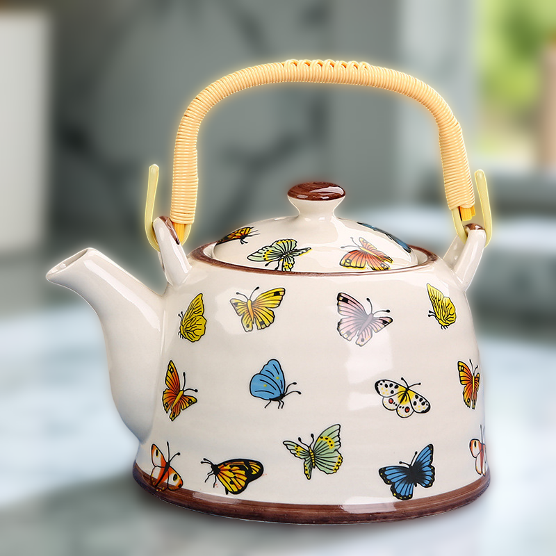 Ceramic teapot with butterfly designs on a blurred background