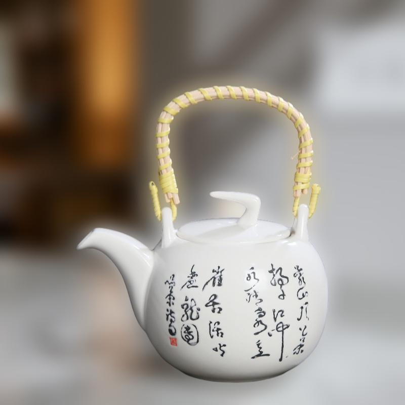 White teapot with black text and a yellow handle on a blurred background