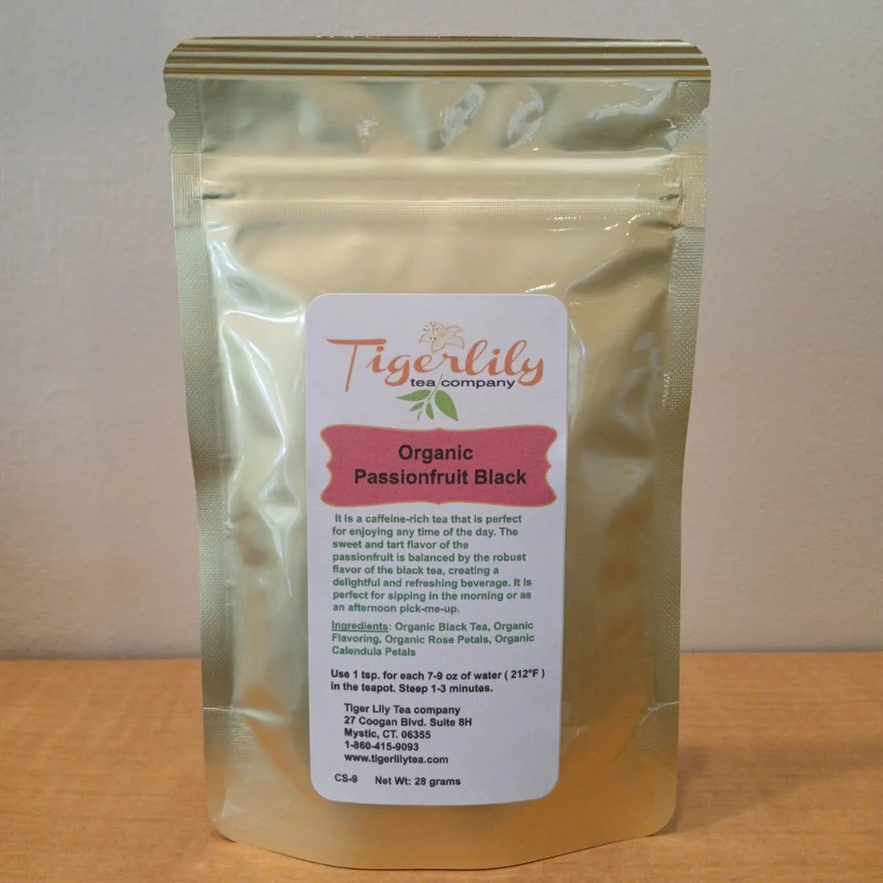 Tigerlily Organic Passionfruit Black tea package on a wooden surface with a white background