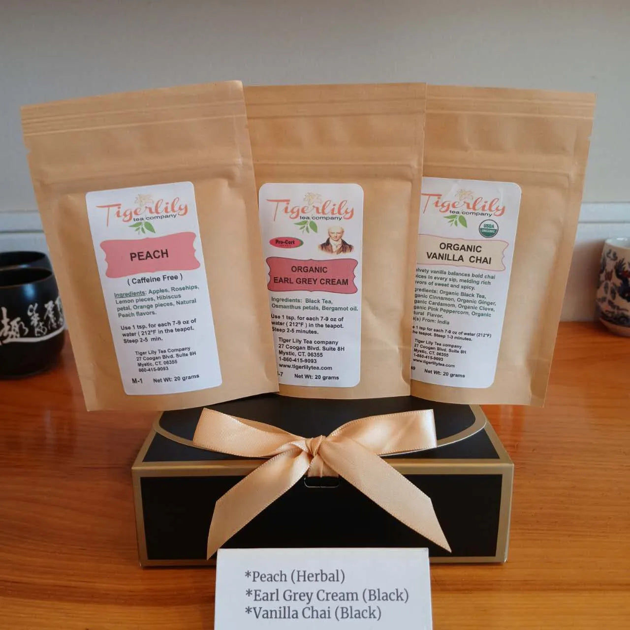 Three packages of Tigerlily tea with labels on a wooden surface.