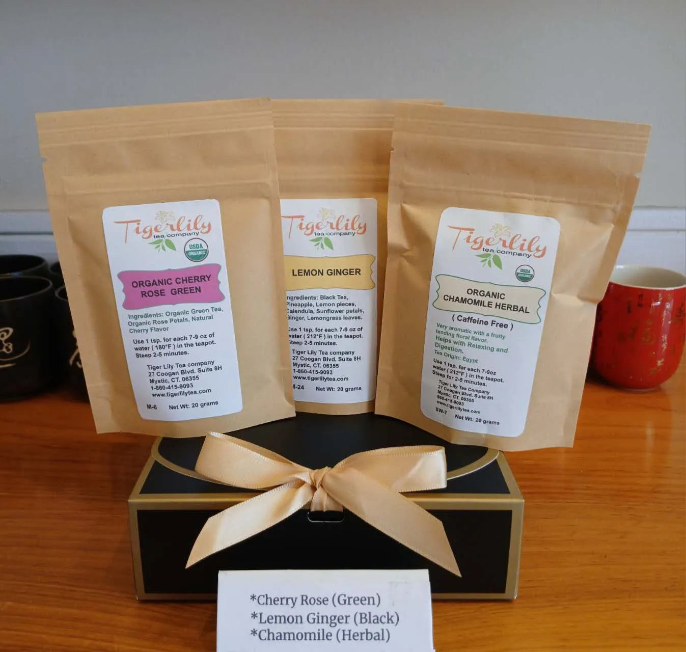 Three Tigerlily tea packages on a stand with a white background