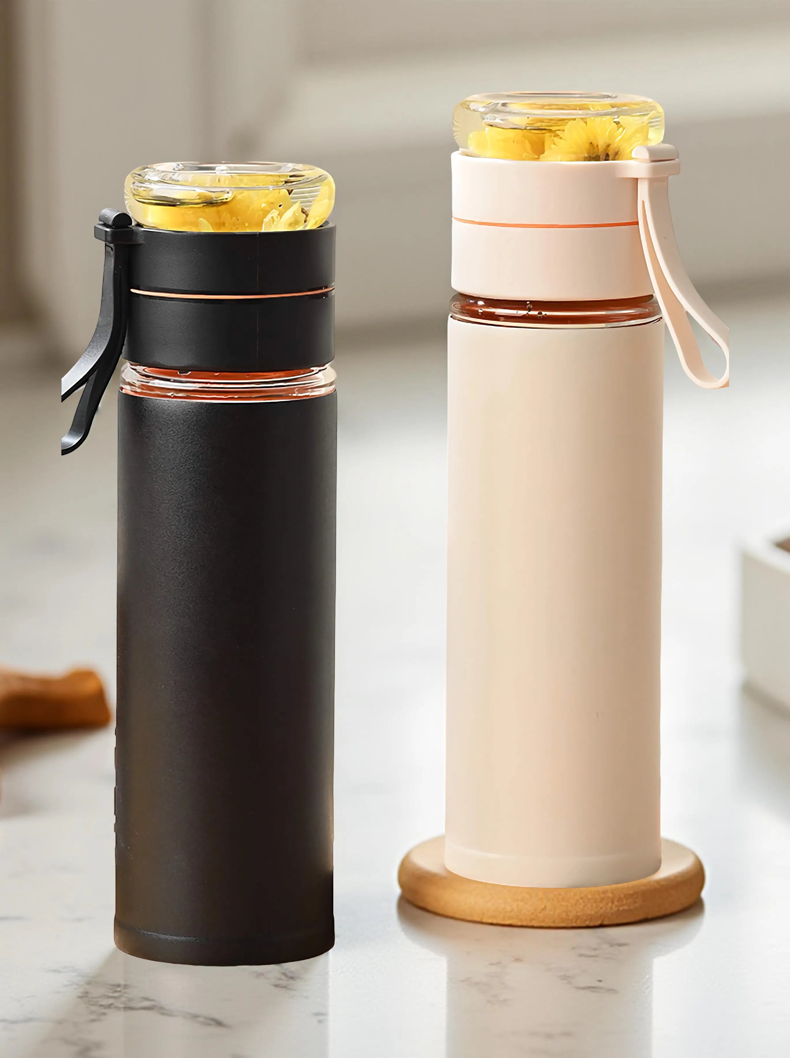 Two insulated travel mugs, one black and one beige with a wooden base, on a marble surface.